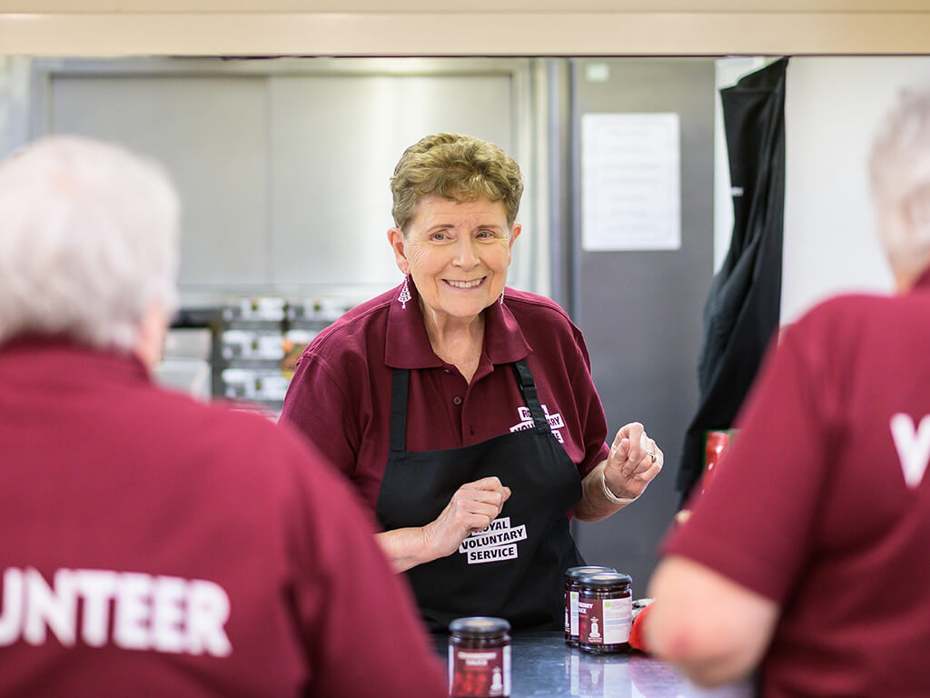 A group of Royal Voluntary Service lunch club volunteers smiling together 