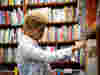 A younger volunteer selecting books at a library for a home library service 