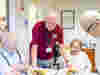 A Royal Voluntary Service volunteer serving meals to a couple of clients at a lunch club 