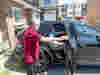 A Royal Voluntary Service driving volunteer supporting a client into the back of a car