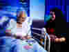 A Royal Voluntary Service volunteer playing cards with a patient who is sitting in bed 