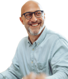 A man in a light blue shirt wearing round glasses with a beard smiling