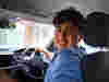A young volunteer driver looking back at his passenger in the back seat and smiling 