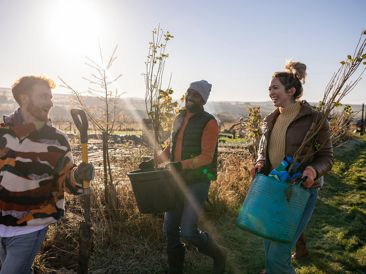 A group of gardening volunteers outside carrying pots with plants 