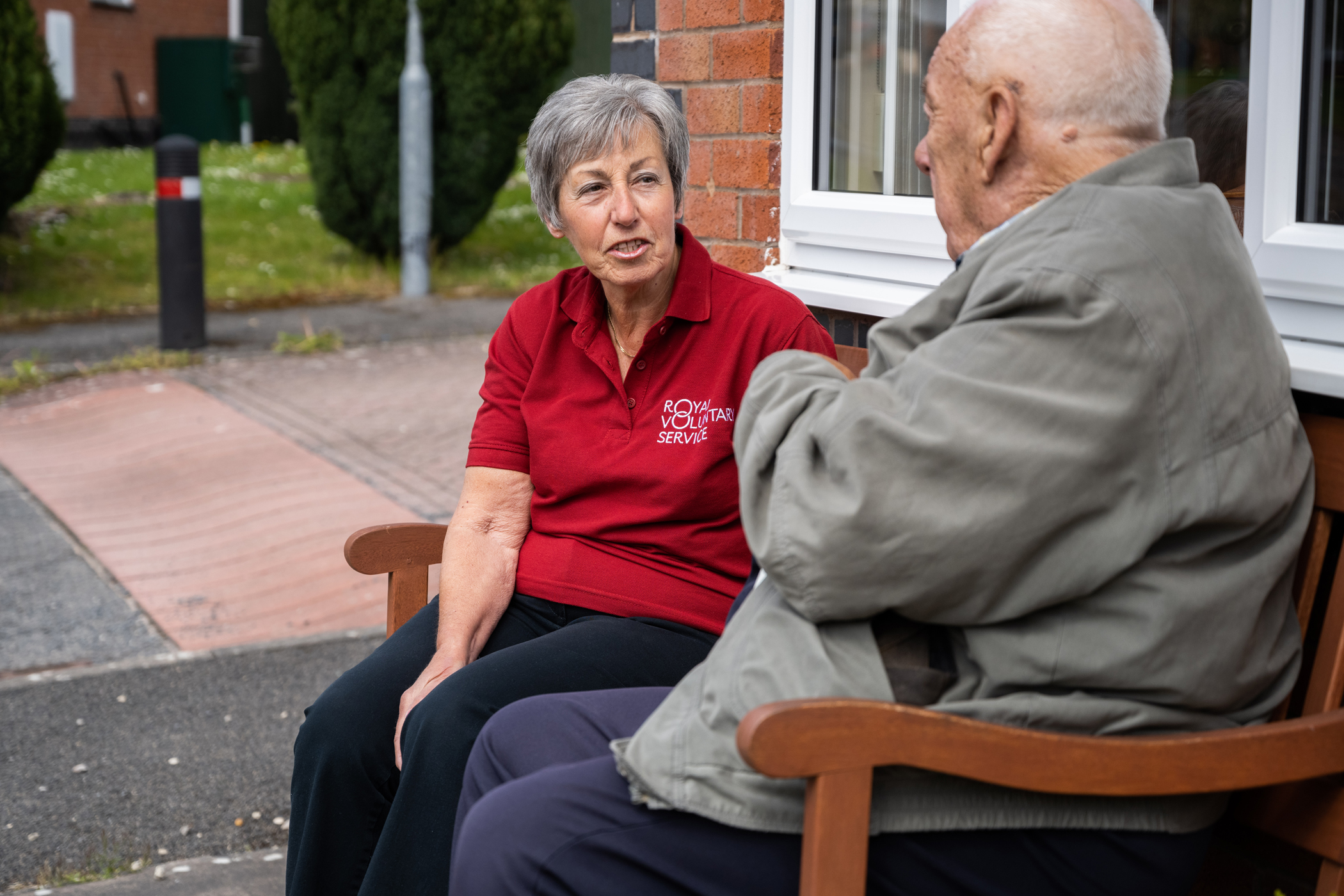 Royal Voluntary Service volunteer chatting on a bench