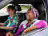 A female volunteer giving a lift to an older woman who is smiling