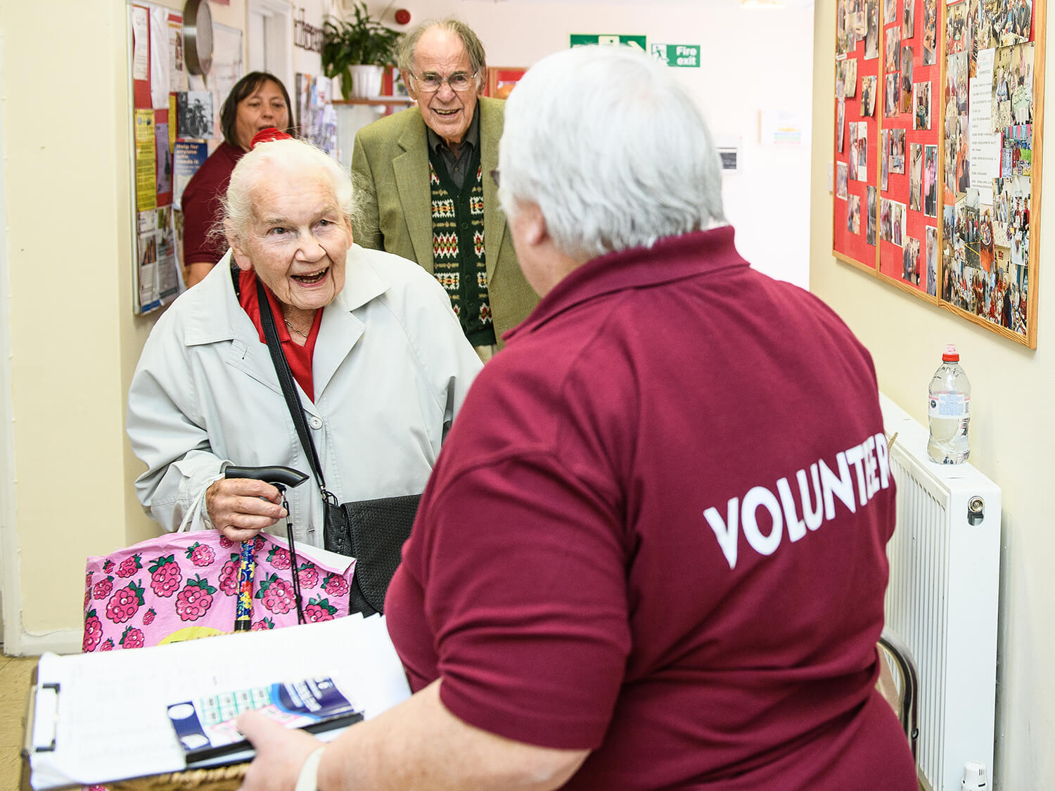 Older people being welcomed into Royal Voluntary Service Cornhill Centre by a volunteer 