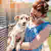A volunteer holding a small dog at an animal shelter