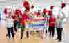 A group of people cheering at a cheque presentation of £5 million thanks to players of People’s Postcode Lottery
