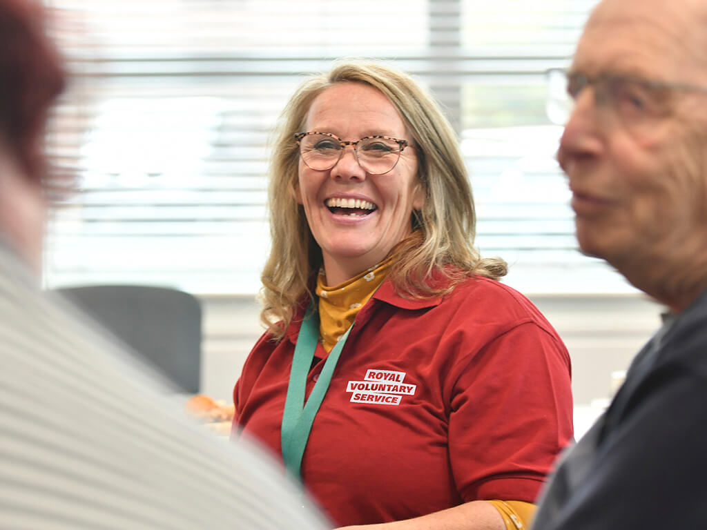 A volunteer wearing a branded tshirt smiling with colleagues
